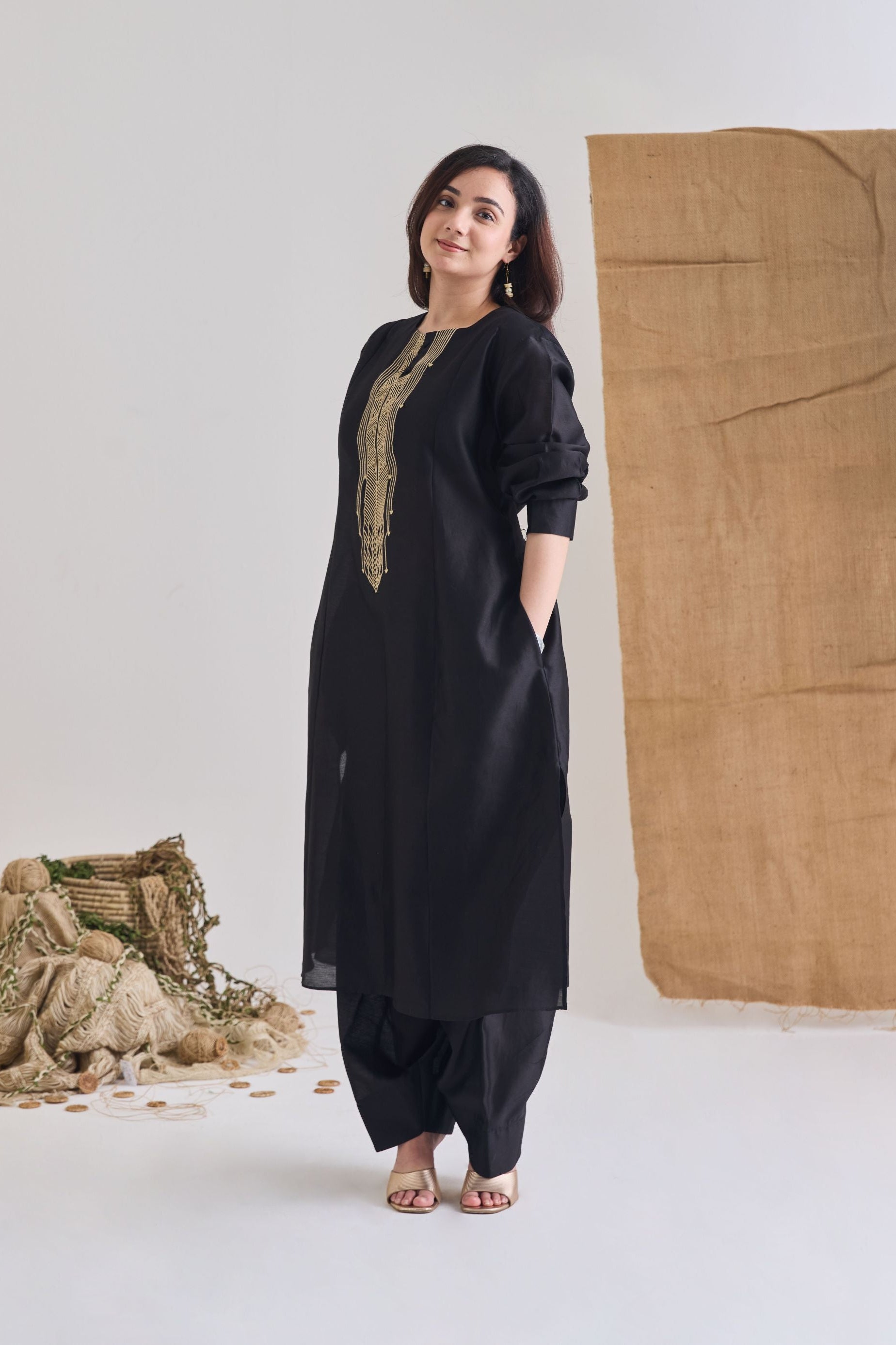 Side view of Black Chanderi long paneled kurta with side pockets and raw jute embroidery on neckline and salwar bottoms
