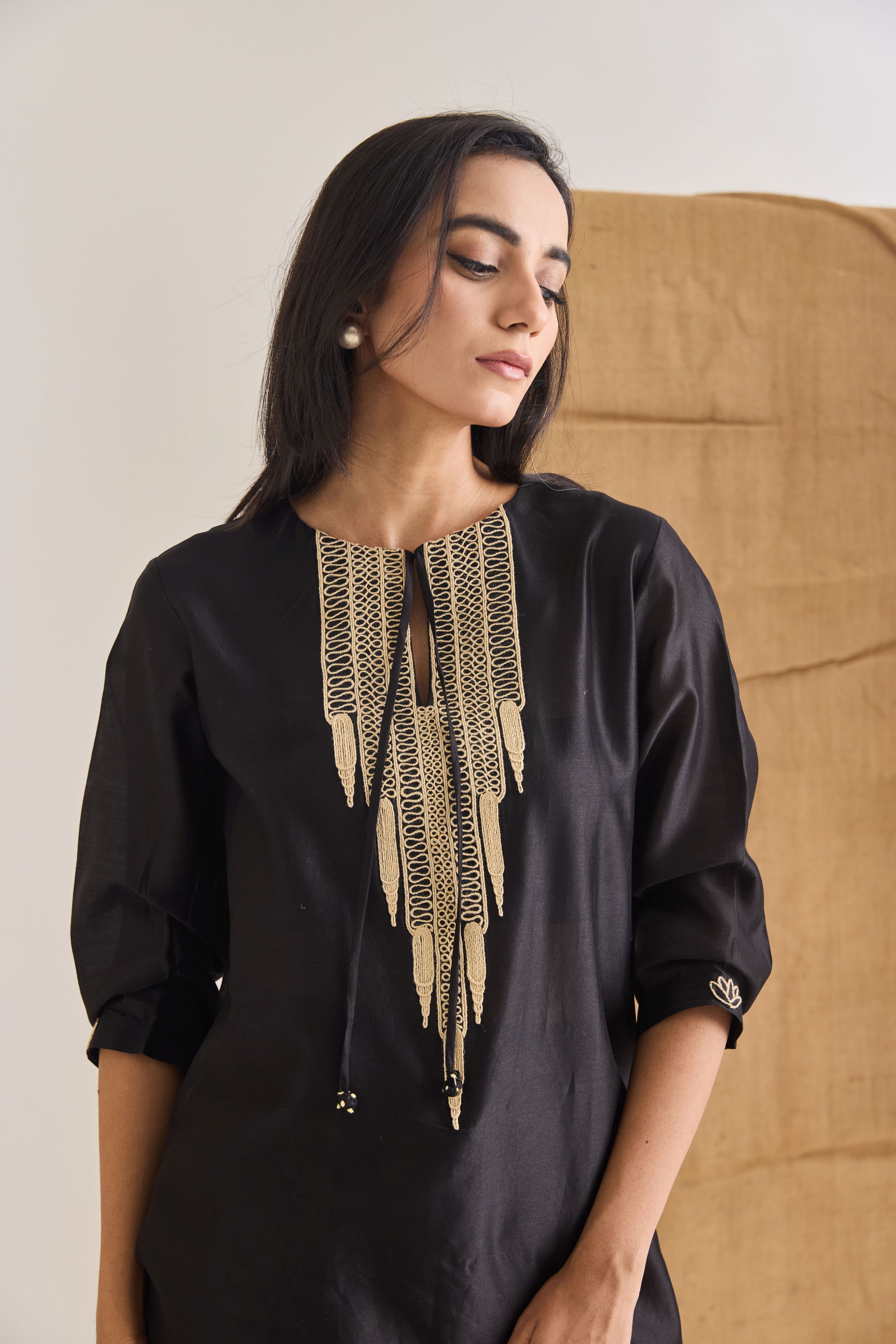 Close-up of raw jute embroidery on the neckline of black Chanderi short kurta with Front ties and 3/4th length sleeves.