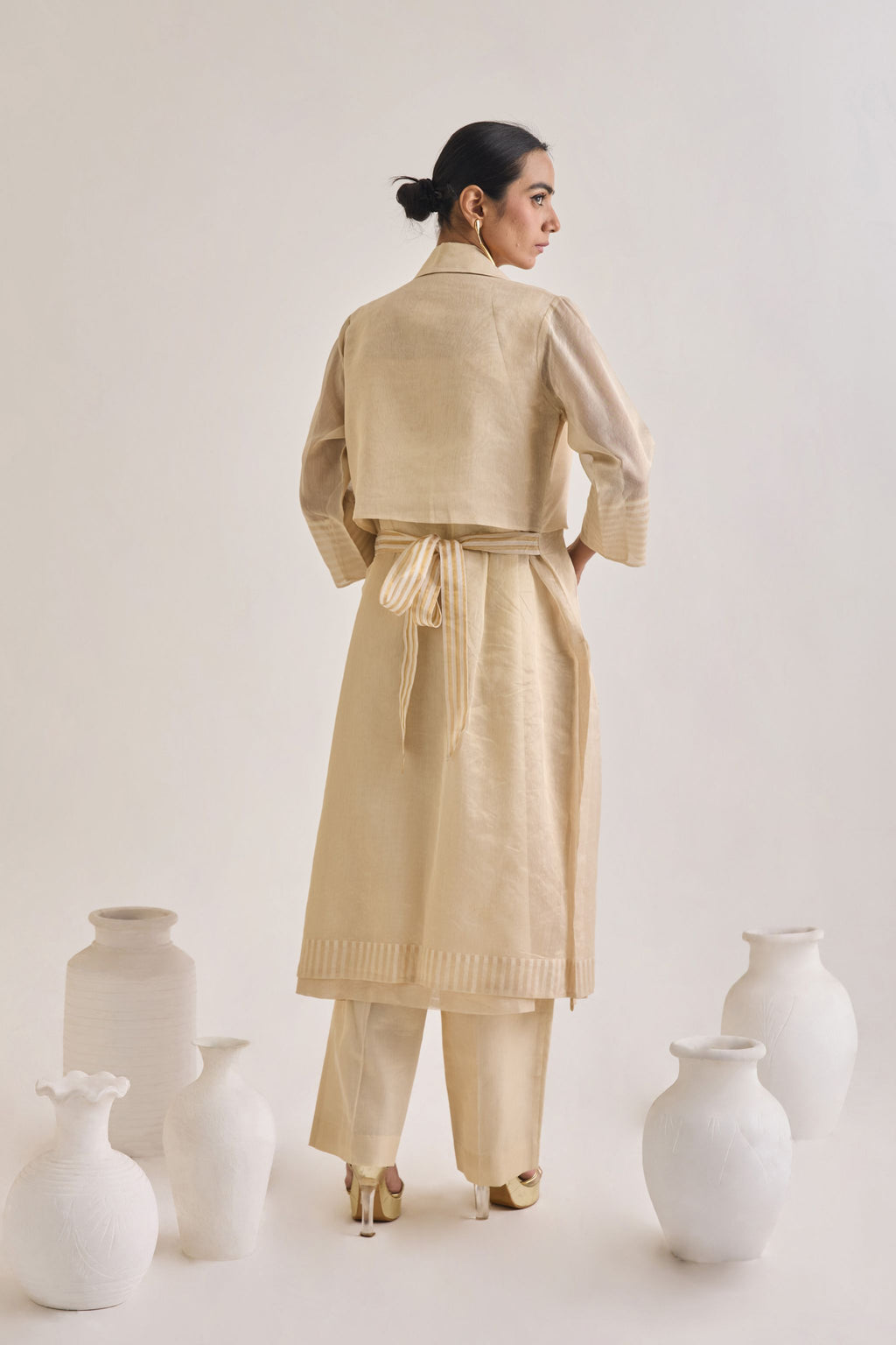 Back view of Chanderi set with a Long coat having notched collar and a back knot design, Fringed stripes  Kurta and crease pants