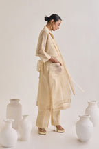 Side view of Chanderi set with a Long coat having notched collar and a back knot design, Fringed stripes  Kurta and crease pants