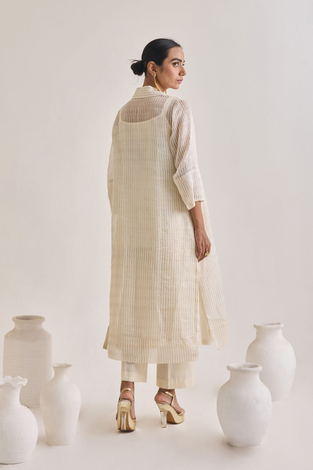 Front view of a off white Cotton fringed set with a Long coat having 3/4th sleeves, Sleeveless cotton Kurta and crease pants.