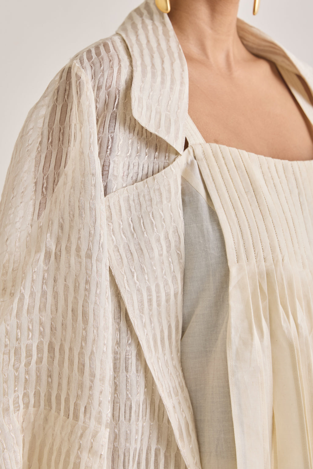 Detailed shot of cotton set having A notched collar coat and a sleeveless kurta with pleats hanging out as fringes at front