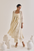 Front view of a off white Cotton fringed set with a Long coat having notched collar, Sleeveless cotton Kurta with Front fringes and crease pants.