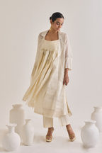Front view of a off white Cotton fringed set with a Long coat having notched collar, Sleeveless cotton Kurta with Front fringes and crease pants.