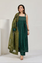 Model in dark green long pure silk strappy kurta with gold thread yoke and silk pants, without coat, front view