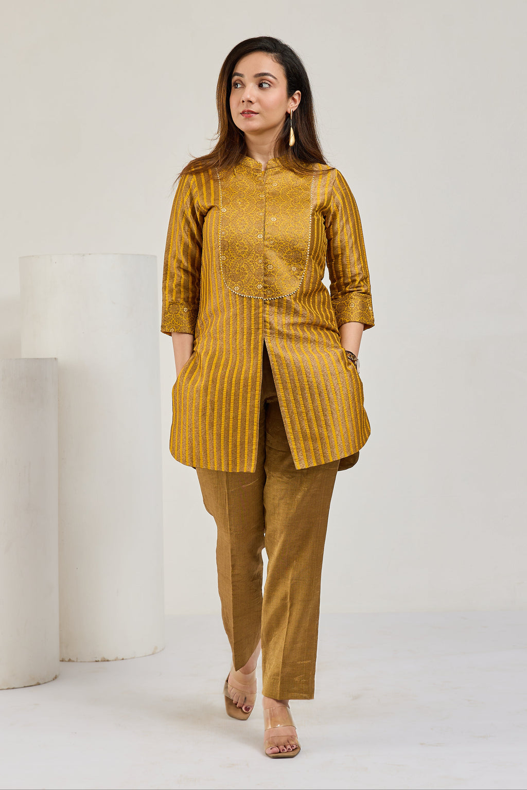 Model in mustard gold front-open Kimkhab kurta with 3/4 sleeves and tissue crease pants, looking to the left