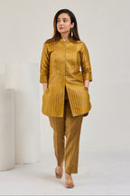 Model in mustard gold front-open Kimkhab kurta with 3/4 sleeves and tissue crease pants, looking to the left