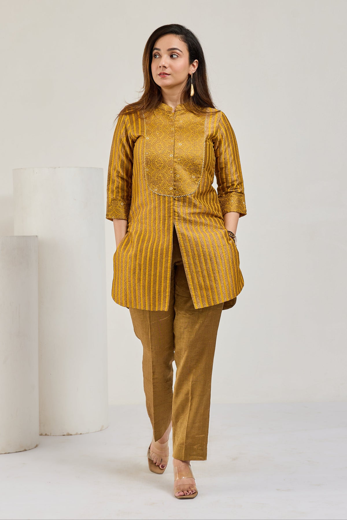 Model in mustard gold front-open Kimkhab kurta with 3/4 sleeves and tissue crease pants, looking to the left