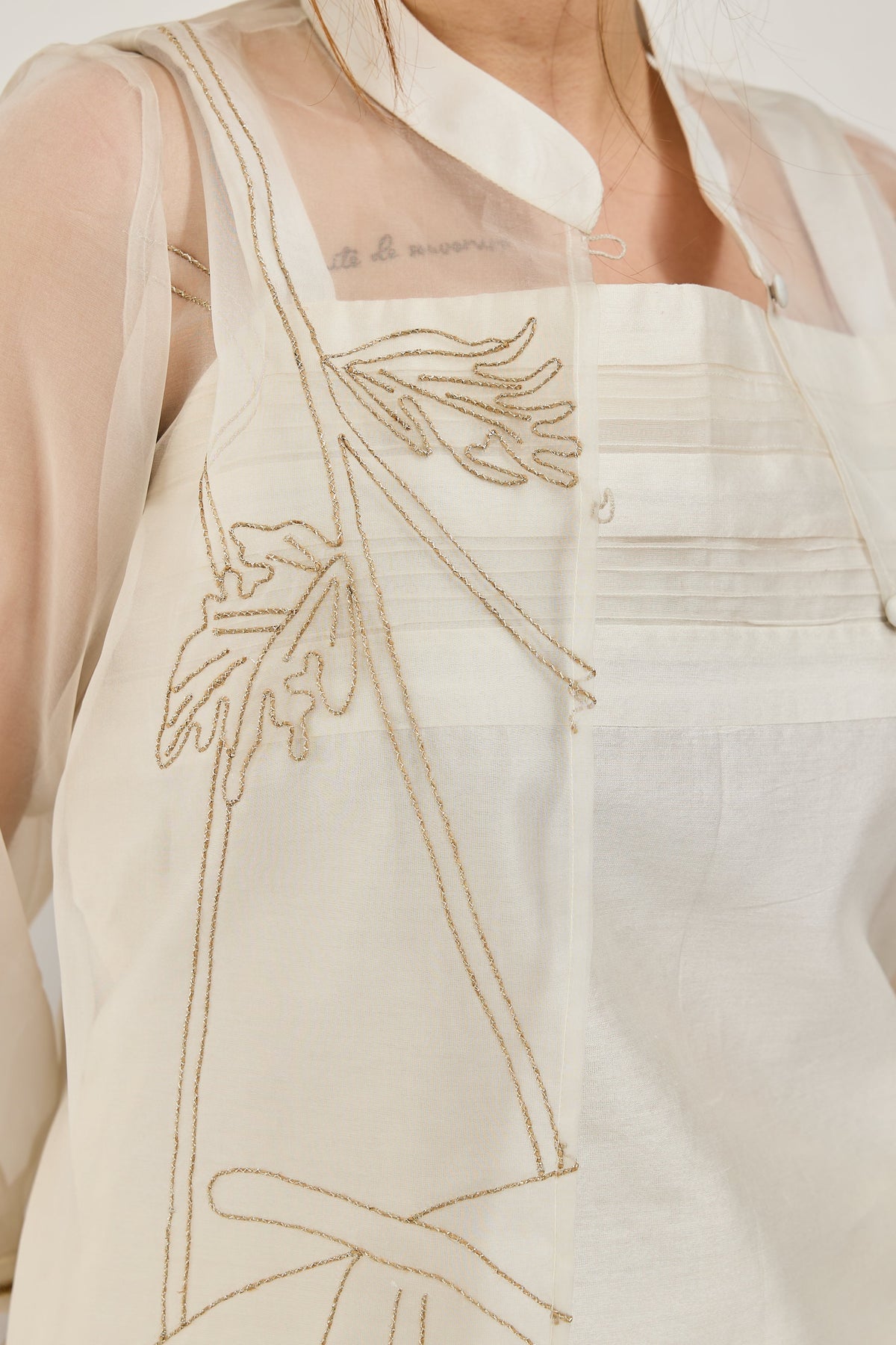 Close-up of hand jute and zari embroidery with seed beads on a white organza jacket
