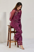 Model seated on a chair in a wine Chanderi co-ord set with sheer organza jacket