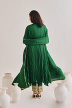 Back profile of a Green suit with 3/4th sleeves and a tie up neck with salwar made out of crushed silk fabric with Golden gota detail and accessorized with a Drawstring Bag and a silk and lace dupatta 