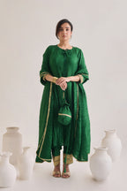 Green suit with 3/4th sleeves and a tie up neck with salwar made out of crushed silk fabric with Golden gota detail and accessorized with a Drawstring Bag