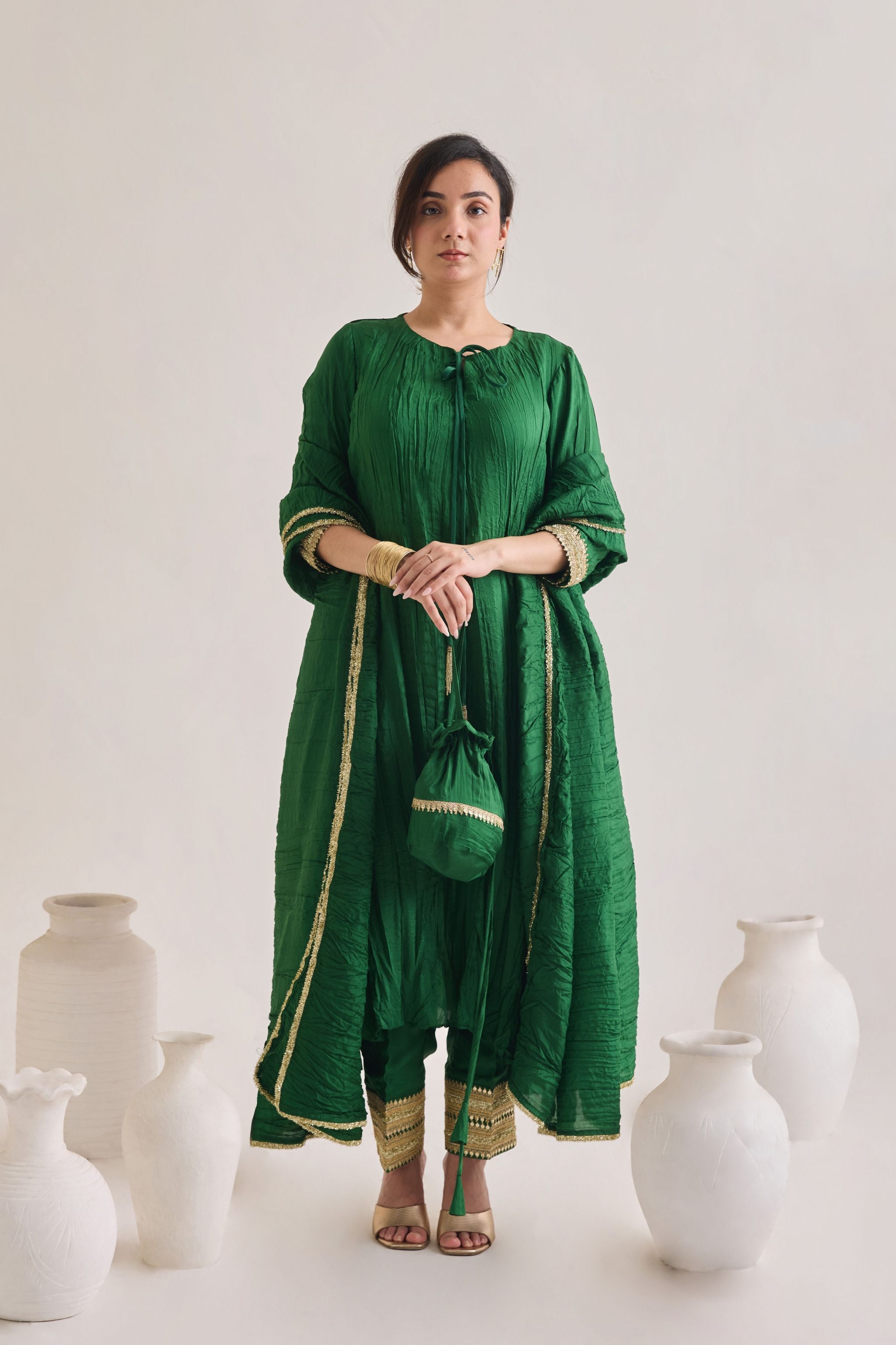 Green suit with 3/4th sleeves and a tie up neck with salwar made out of crushed silk fabric with Golden gota detail and accessorized with a Drawstring Bag