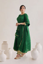 Side profile of a Green suit with 3/4th sleeves and a tie up neck with salwar made out of crushed silk fabric with Golden gota detail and accessorized with a Drawstring Bag and a silk and lace dupatta 