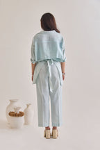 Back view of Pastel Blue Cotton-Linen Shirt with Sleeves rolled up and back tied with a knot to make it look elevated.