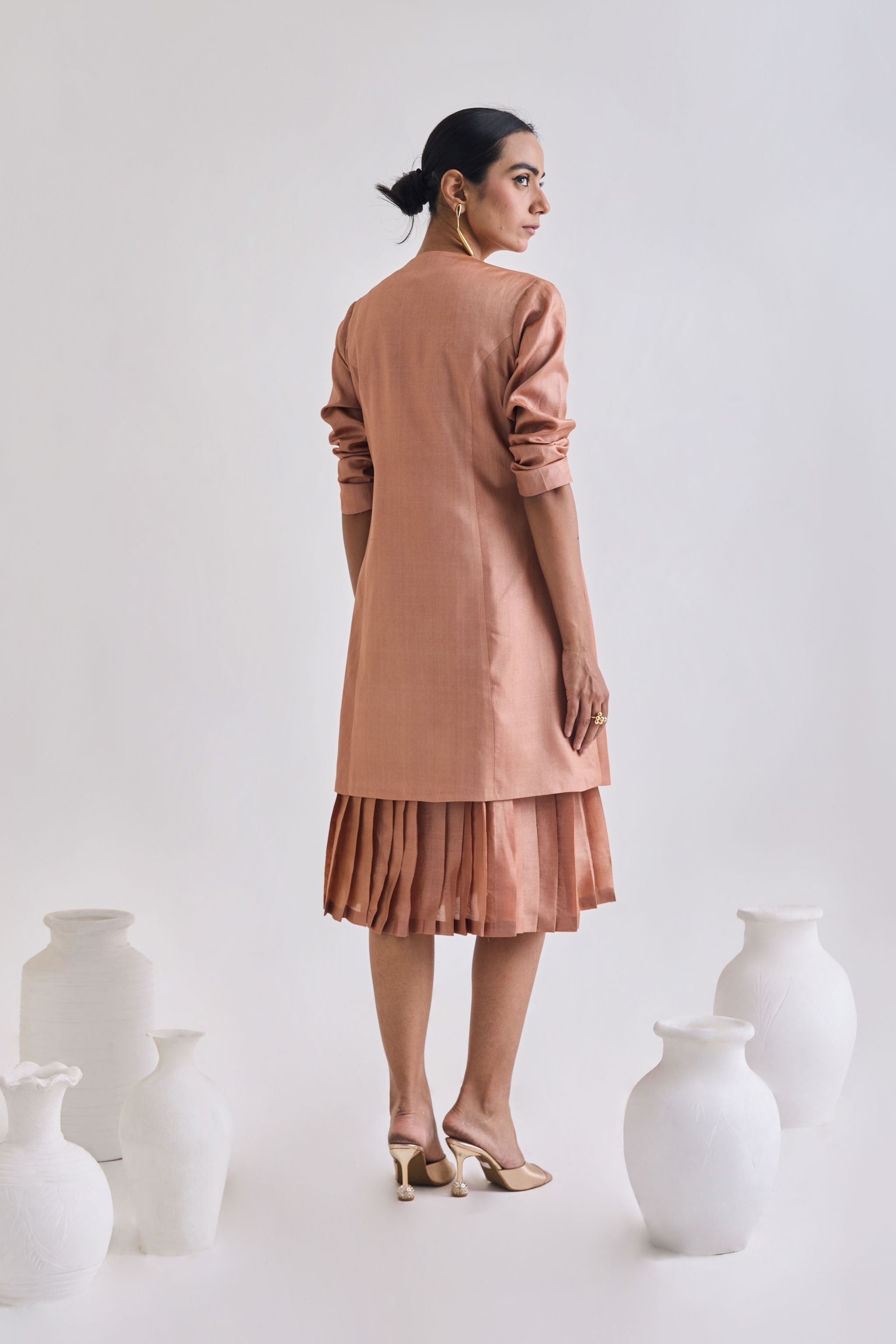 Back view of Tussar sleeveless pleated dress with Full sleeve tussar coat with full sleeve rolled up to elbow 