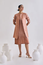 Front view of sleeveless pleated dress with Full sleeve tussar coat with slant pockets and full sleeve rolled up to elbow