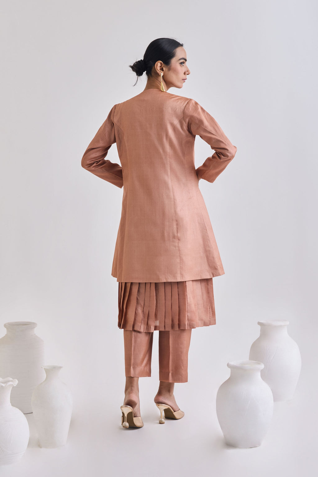Back view of Pure tussar set with a pleated sleeveless dress, a coat which has long sleeves, and a pair of tailored pants.