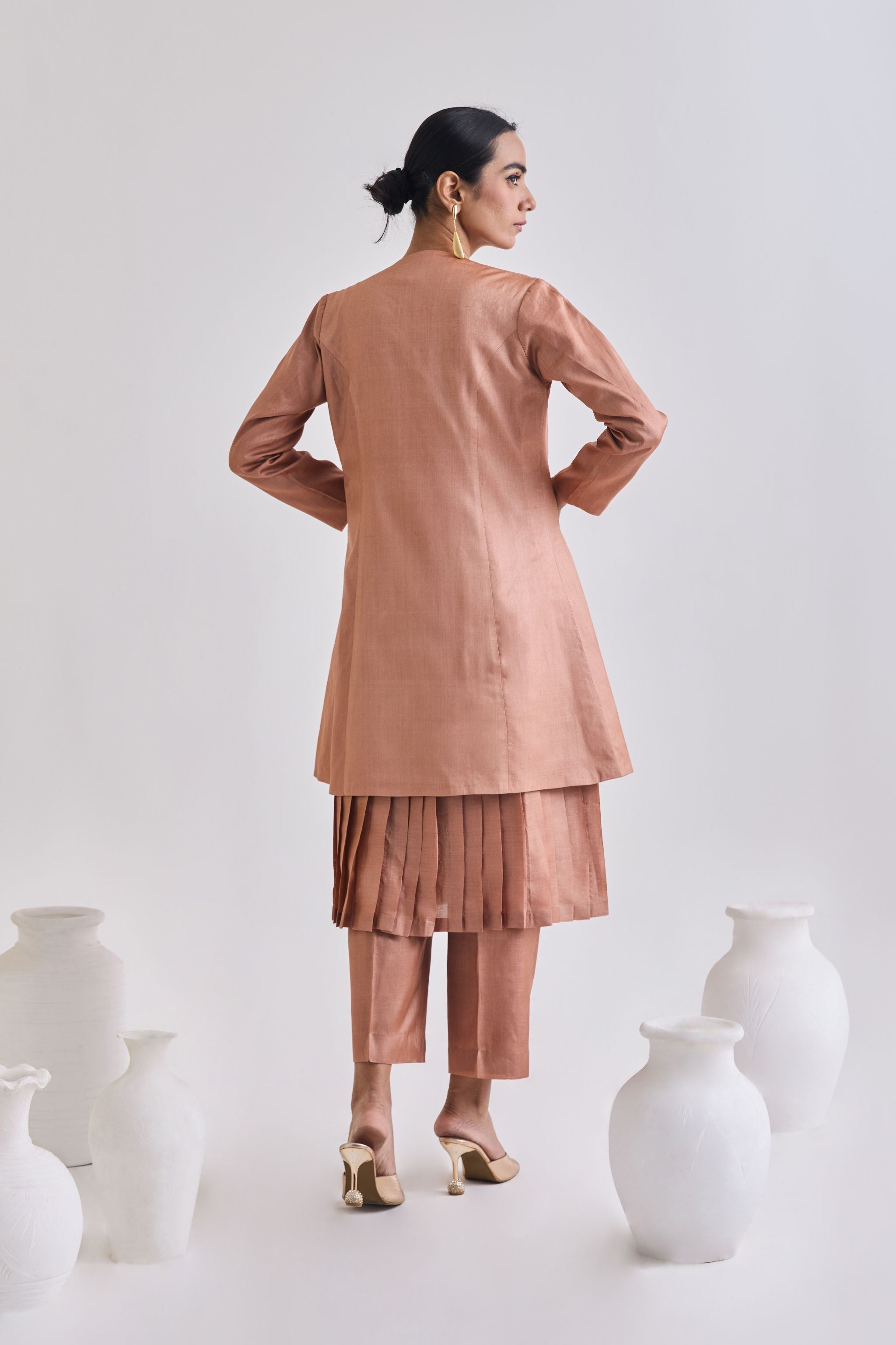 Back view of Pure tussar set with a pleated sleeveless dress, a coat which has long sleeves, and a pair of tailored pants.