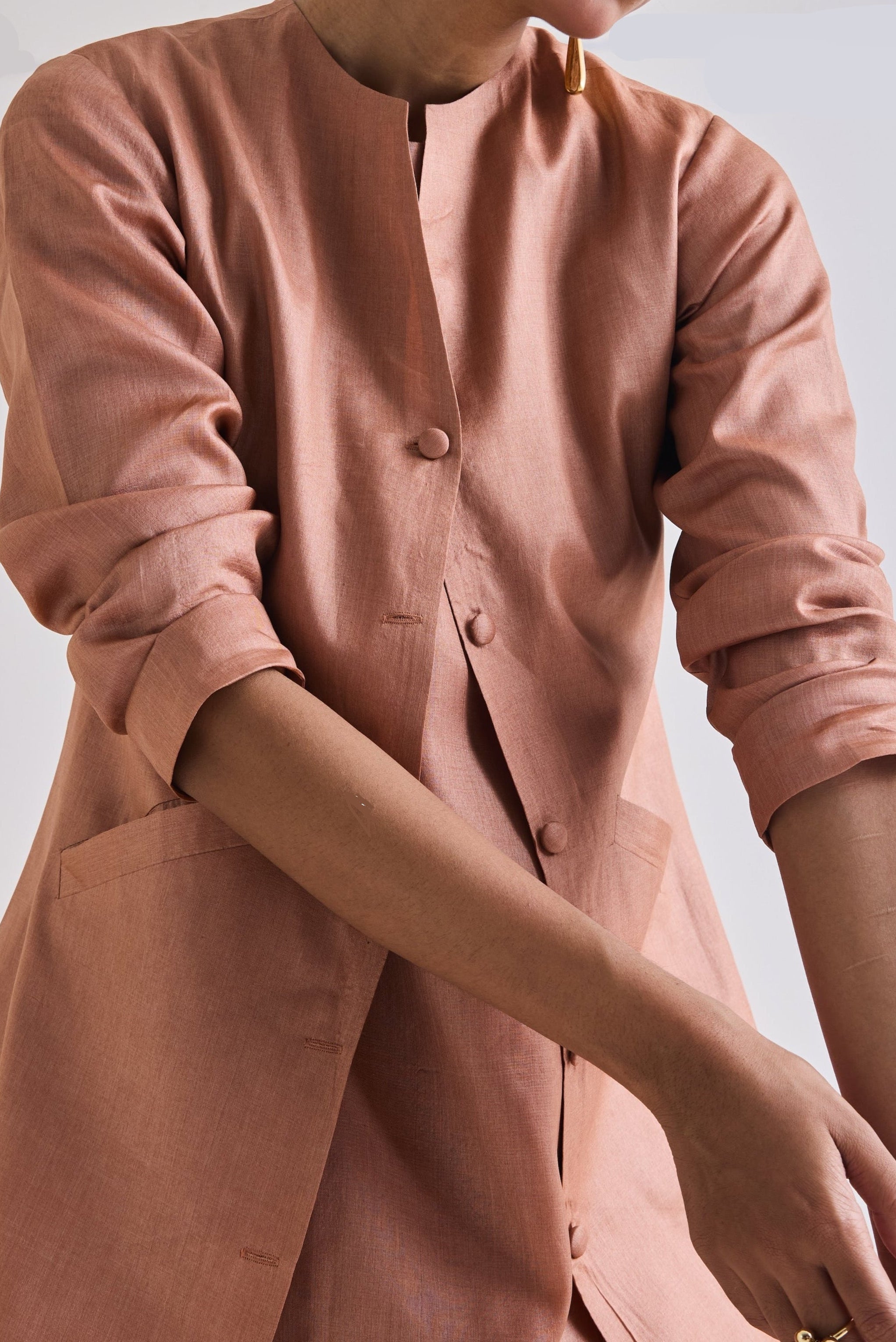 Close-up details of Pure tussar set with a sleeveless dress and coat with slant pockets and long sleeves rolled up to elbow.