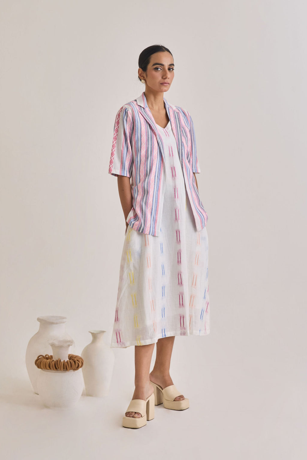 Front profile of a white cotton dress with weaved multicolour design and a blazer with elbow length sleeves with pink and blue stripes woven to the fabric