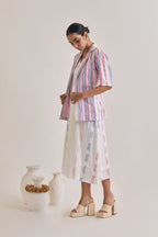 Side profile of a white cotton dress with weaved multicolour design and a blazer with elbow length sleeves with pink and blue stripes woven to the fabric