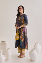 Side profile of multicolour suit made out out of crushed silk fabric with 3/4th length sleeves having gota border at sleeve opening and Dori neckline, paired with a pair of mustard salwar with golden gota and a mustard gota Drawstring bag.